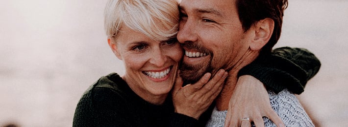 Frau umarmt Mann, beide lachen