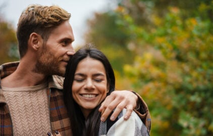 Ein Mann hält eine Frau im Arm, sie lächelt.