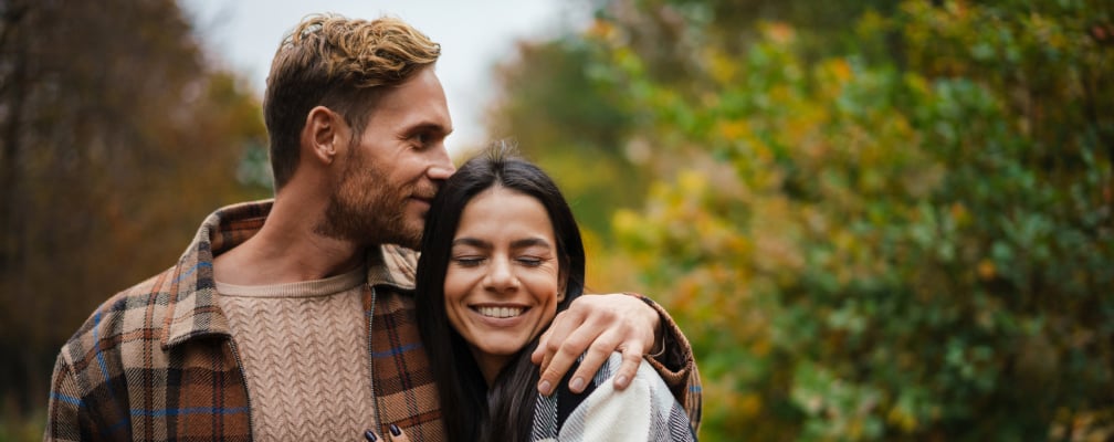 Ein Mann hält eine Frau im Arm, sie lächelt.
