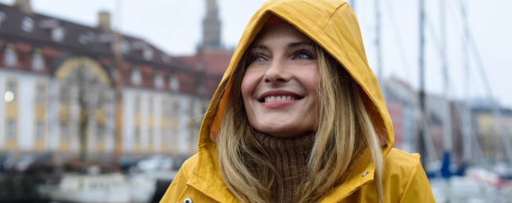 Eine Frau in einem gelben Mantel lächelt glücklich.