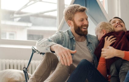 Eine lachende Familie mit einem kleinen Kind im Arm.