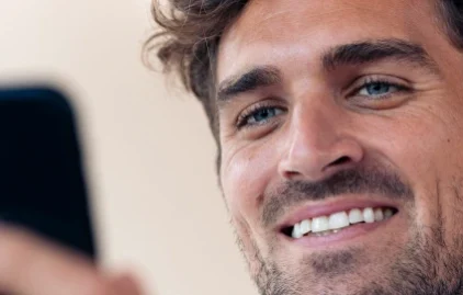 Mann mit Smartphone lächelt beim Dating über WhatsApp