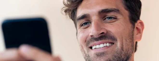 Mann mit Smartphone lächelt beim Dating über WhatsApp