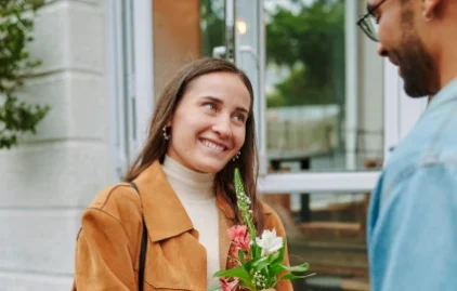 Eine Frau bringt einem Mann einen Blumenstrauß zum zweiten Date mit.